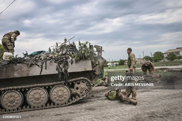 Ukrainian servicemen assist their comrades not far from the frontline in the eastern Ukrainian region of Donbas, on May 21, 2022.