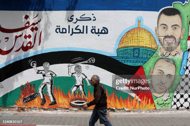 Palestinians walk past a mural on the first anniversary of the May 2021 conflict between Israel and Hamas, in Gaza city on May 21, 2022. The 2021...