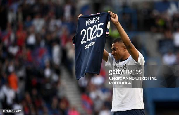 Paris Saint-Germain's French forward Kylian Mbappe poses with a jersey after the announcement he staying at PSG until 2025 before the French L1...