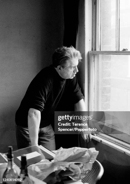 Irish-born British figurative artist Francis Bacon looking out of a window at his studio in London on 11th March 1975.