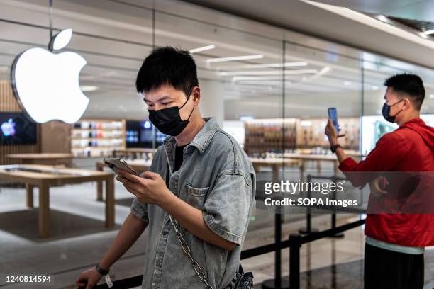 People wearing masks wait in line following social distancing rules at the official opening of the new Apple Store in Wuhan International Plaza,...