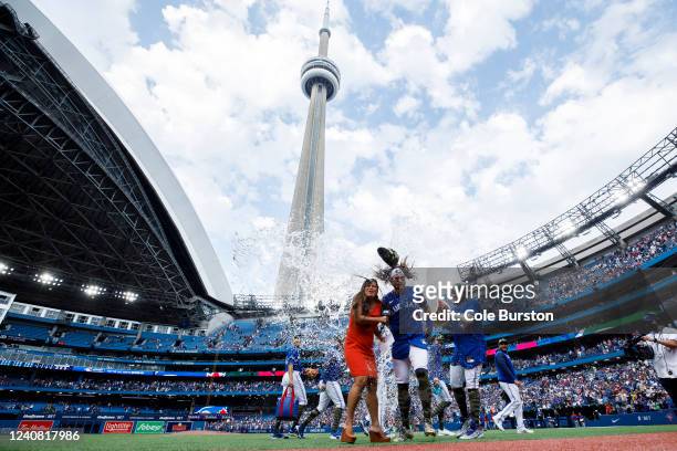 Vladimir Guerrero Jr. #27 of the Toronto Blue Jays throws water on Bo Bichette as he is interviewed following their MLB game victory against the...