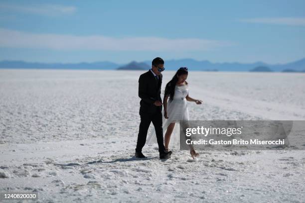 Couple walk during a mass wedding at Uyuni Salt Flats on May 20, 2022 in Uyuni, Bolivia. The civil registration organized an open opportunity for...