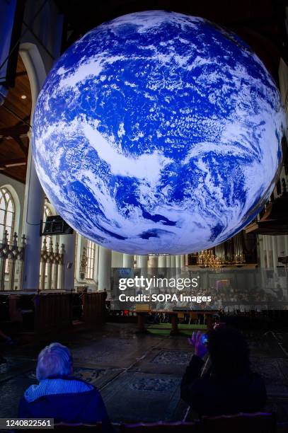 People are seen taking photos of the big Earth ball placed inside the church. Gaia is a touring artwork by UK artist Luke Jerram. Measuring seven...