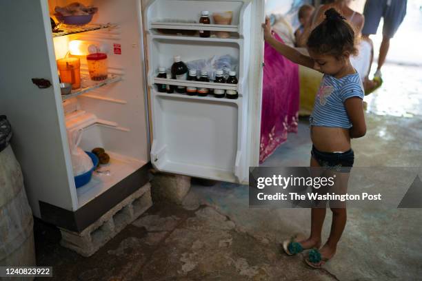 Laurent Alemany holds the door to the fridge open looking for food.. Laurent loves milk and wants it everyday for breakfast. She also has to share...