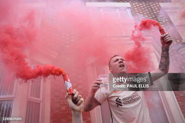 Liverpool's supporter holds red smoke flares as he cheers in the streets prior to the English Premier League football match between Liverpool and...