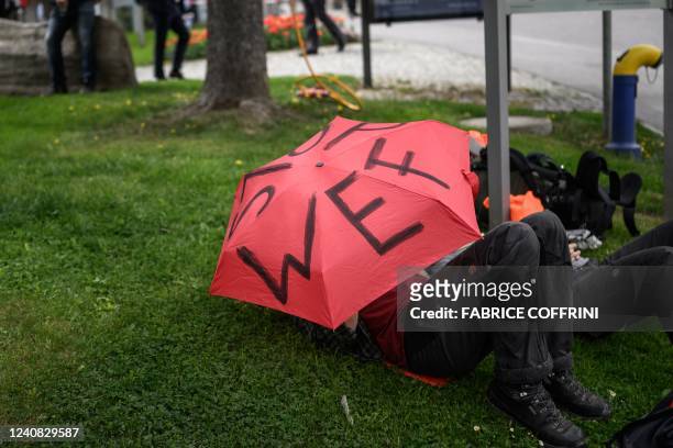 Protesters lays under an umbrella during a demonstration against the World Economic Forum during the WEF annual meeting in Davos on May 22, 2022.