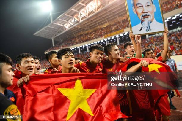 Vietnam's players hold their national flags and a portrait of Ho Chi Minh after winning the men's football final match against Thailand during the...