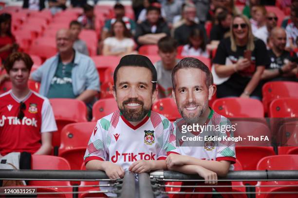 Wrexham fan with novelty masks showing Wrexham Owners Rob McElhenney , and Ryan Reynolds , with a home made top hat inside Wembley Stadium during the...