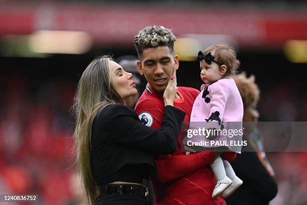 Liverpool's Brazilian midfielder Roberto Firmino is kissed by his wife as he celebrates with their daughter during a lap of honour at the end of the...