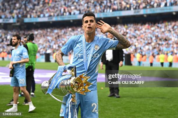 Manchester City's Portuguese defender Joao Cancelo celebrates with the Premier League trophy on the pitch after the English Premier League football...