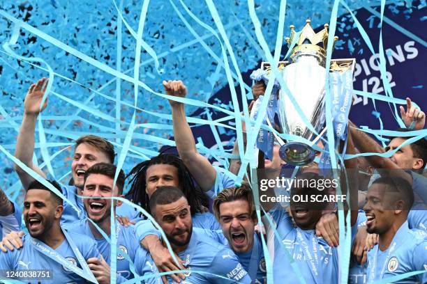 Manchester City's Brazilian midfielder Fernandinho lifts the Premier League trophy as City players celebrate on the pitch after the English Premier...