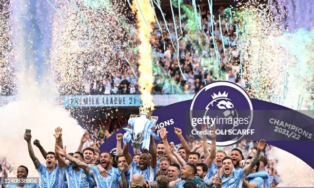 Manchester City's Brazilian midfielder Fernandinho lifts the Premier League trophy as City players celebrate on the pitch after the English Premier...