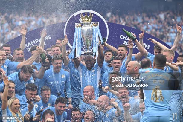 Manchester City's Brazilian midfielder Fernandinho lifts the Premier League trophy as City players celebrate on the pitch after the English Premier...
