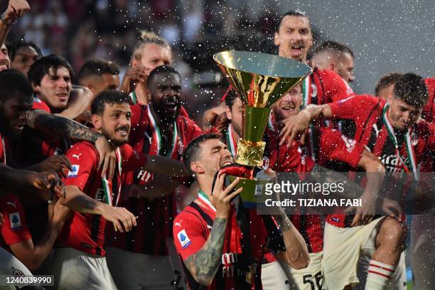 Milan's Italian defender Alessio Romagnoli bites the cup as AC Milan's players celebrate with the winner's trophy after AC Milan won the Italian...