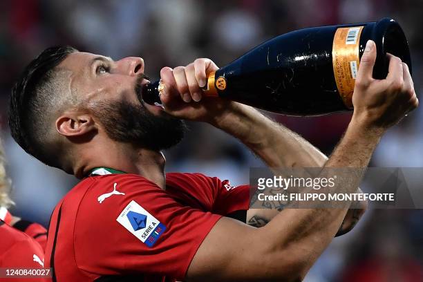 Milan's French forward Olivier Giroud drinks sparkling wine as he celebrates during the winner's trophy ceremony after AC Milan won the Italian Serie...