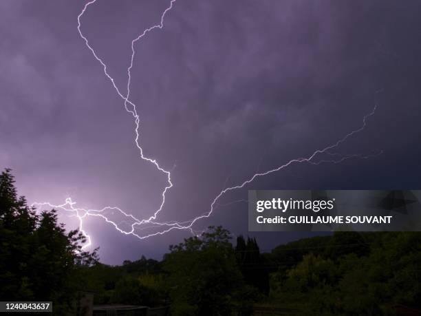 Photograph shows lightning discharges from a thundercloud over trees in Montlouis-sur-Loire, Central France, on May 22, 2022. - Meteo France has...