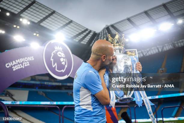 Pep Guardiola the head coach / manager of Manchester City kisses the Premier League trophy during the Premier League match between Manchester City...