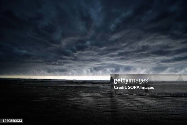 Man walks on the seaside before a cloud burst of rain at the Udaipur, Digha, approximately 200 km from Kolkata. India Meteorological Department has...