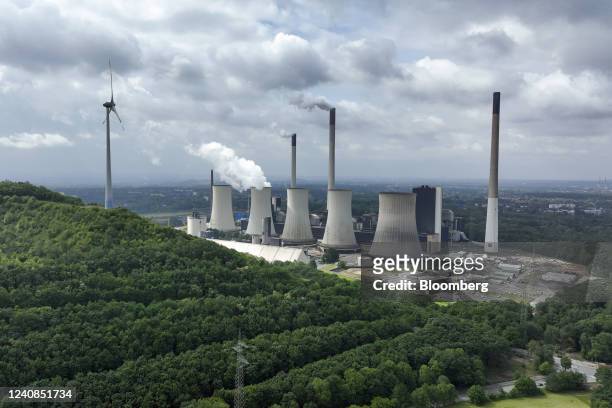 Wind turbine on a hillside near chimneys and a cooling tower emitting vapor at the Scholven coal-fired power plant, operated by Uniper SE, in...