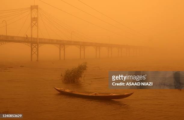 Fishing boat weighted with rocks lies stationary in the Euphrates river near a pedestrian bridge amidst a heavy dust storm in the city of Nasiriyah...