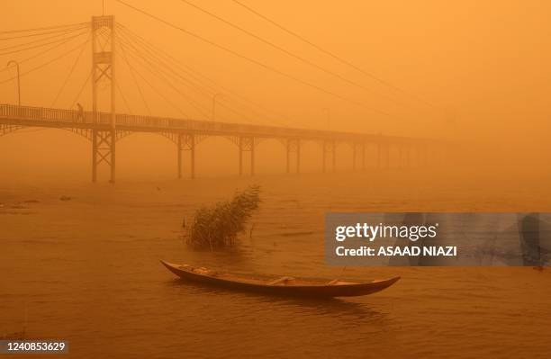 Fishing boat weighted with rocks lies stationary in the Euphrates river near a pedestrian bridge amidst a heavy dust storm in the city of Nasiriyah...