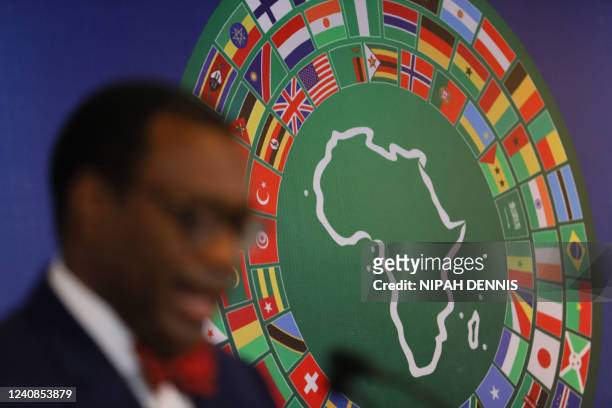 Logo with various national flags of countries around the world are seen as Akinwumi Adesina, president of the African Development Bank Group, speaks...