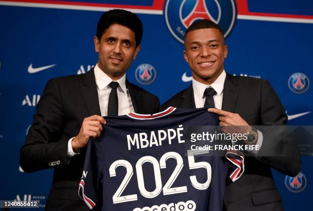 Paris Saint-Germain's CEO Nasser Al-Khelaifi and French forward Kylian Mbappe pose with a jersey at the end of a press conference at the Parc des...