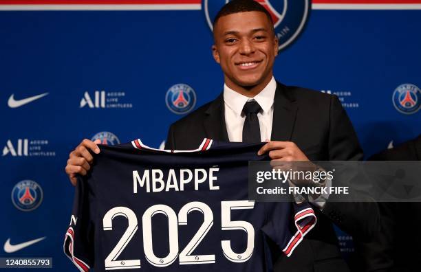 Paris Saint-Germain's French forward Kylian Mbappe poses with a jersey at the end of a press conference at the Parc des Princes stadium in Paris on...