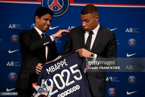 Paris Saint-Germain's CEO Nasser Al-Khelaifi and French forward Kylian Mbappe pose with a jersey at the end of a press conference at the Parc des...