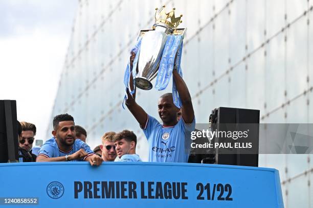 Manchester City's Brazilian midfielder Fernandinho holds up the trophy as Manchester City's players begin an open-top bus parade through the streets...