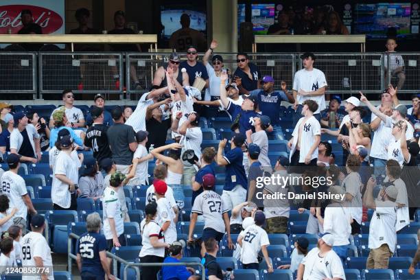 Fans reach for a home run ball during the game between the Chicago White Sox and the New York Yankees at Yankee Stadium on Sunday, May 22, 2022 in...