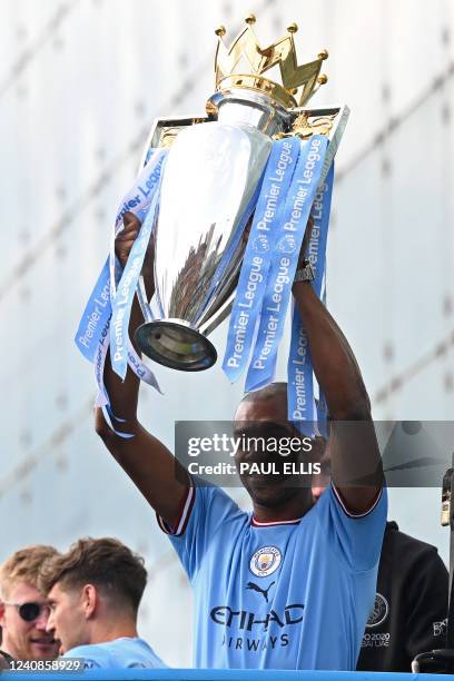 Manchester City's Brazilian midfielder Fernandinho holds up the trophy as Manchester City's players begin an open-top bus parade through the streets...