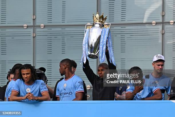 Manchester City's Brazilian midfielder Fernandinho holds up the trophy as Manchester City's players begin an open-top bus parade through the streets...