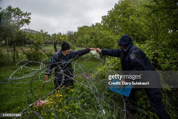 Georgian border police hand food over a barbed wire fence to local farmer, who stands on the Russian controlled territory of South Ossetia in...