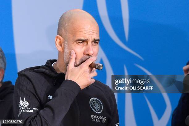 Manchester City's Spanish manager Pep Guardiola smokes a cigar as he attends an event for fans with members of the Manchester City football team...