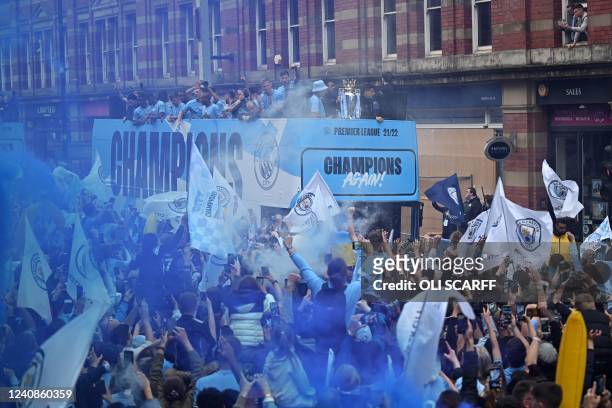 Manchester City's players wave from an open-top bus during a parade through the streets of Manchester in north-west England on May 23 to celebrate...