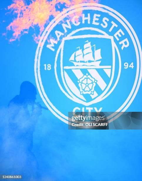 The shadow of Manchester City's Spanish manager Pep Guardiola, smoking a cigar is seen as he attends an event for fans with members of the Manchester...