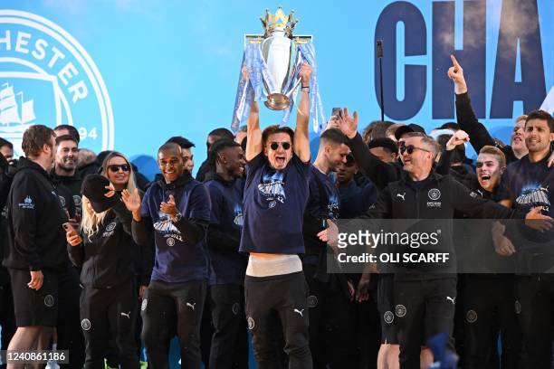 Manchester City's English midfielder Jack Grealish holds up the trophy at an event for fans with members of the Manchester City football team...