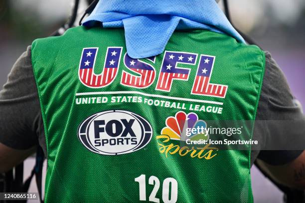 The FOX Sports and NBC Sports logos are displayed on the back of a USFL sideline vest during a USFL football game between the Michigan Panthers and...