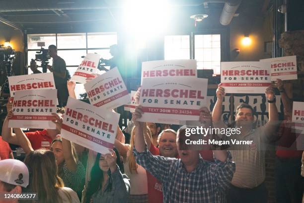 Fans of Heisman trophy winner and Republican candidate for US Senate Herschel Walker hold up signs for him before he speaks at a rally on May 23,...