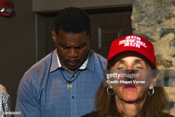 Heisman Trophy winner and Republican candidate for US Senate Herschel Walker prays before speaking at a rally on May 23, 2022 in Athens, Georgia....