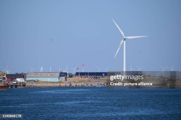 April 2022, Denmark, Hvide Sande: A wind turbine stands against a blue sky near the harbor entrance in Hvide Sande. Photo: Jonas Walzberg/dpa