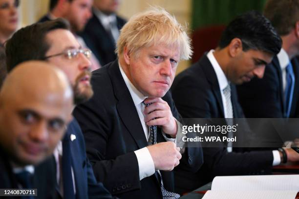 Prime Minister Boris Johnson adjusts his tie at the start of a cabinet meeting at 10 Downing Street on May 24, 2022 in London, England. Photographs...