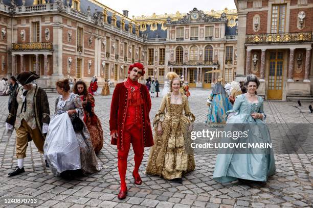 People wearing baroque style costumes pose as they arrive at the Chateau de Versailles Palace to take part in the sixth edition's of the Fetes...