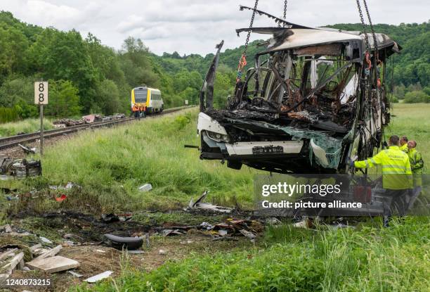 May 2022, Baden-Wuerttemberg, Blaustein: Rescue workers stand by a burned-out bus. This bus came to a standstill on a railroad crossing during a...