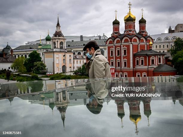 Man wearing a face mask walks past Russian Orthodox cathedrals at the Zaryadye park in Moscow on May 24, 2022.
