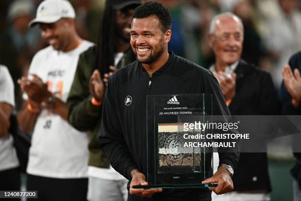 France's Jo-Wilfried Tsonga reacts as he receives a trophy to mark his retirement at the end of his men's singles match against Norway's Casper Ruud...