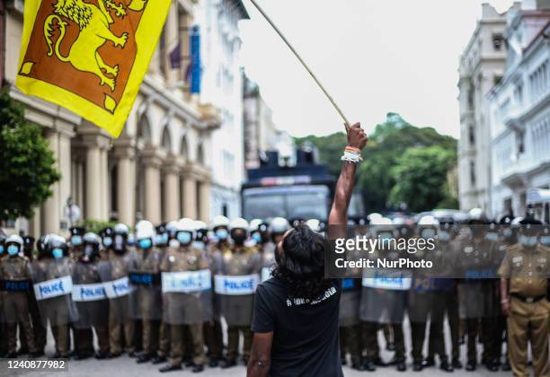 Protester waves the national flag in front of the police brigade during the protest near the president's house in Colombo, Sri Lanka, on May 24,...