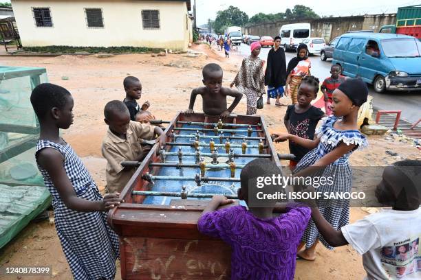 Children enjoy a game of table football in a street of Abobo, a surbub of Abidjan on May 24, 2022.